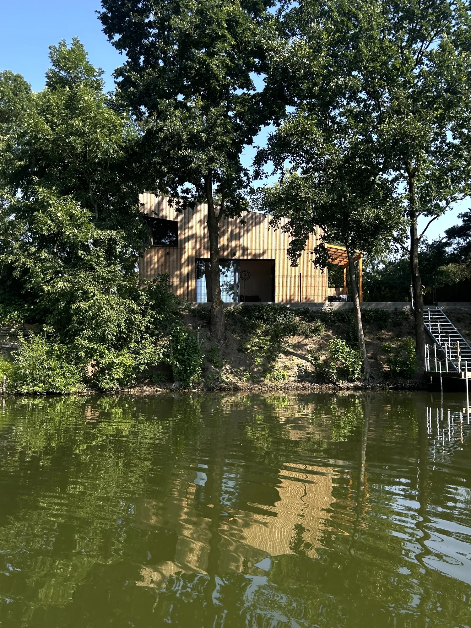 Domek nad hladinou rybníka mezi stromy